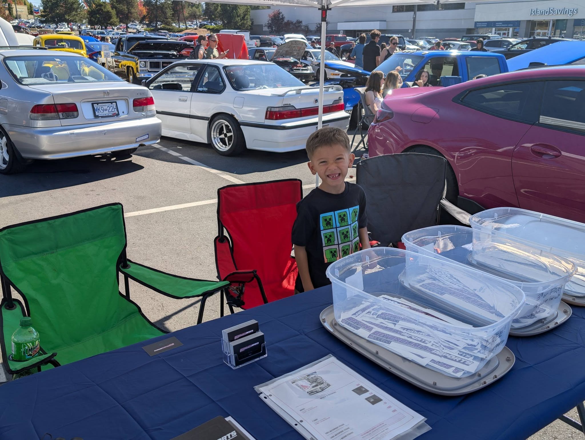 Isaiah running the Beyond Limits Imports booth table at a 2026 Vancouver Island car meet