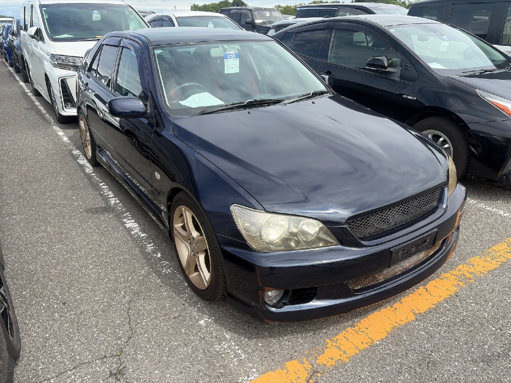 Front three-quarter view of a dark blue Toyota Altezza at USS auction with auction sheet on the dash